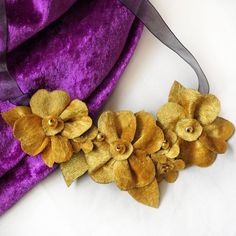 It's great to have versatile accessories. This sumptuous gold velvet floral ribbon necklace can be worn at any length so will suit so many outfits. Such a useful piece of costume jewellery and gorgeous too!This bold statement necklace is also great for those with a metal allergy as it is all fabric, which leaves you free to enjoy any special occasion. Because there are no metal parts, it is also extremely light to wear.Each flower is hand cut and hand sewn and embellished with golden yellow glas Statement Necklace Gold, Velvet Necklace, Bold Statement Necklaces, Felt Necklace, Flower Statement Necklace, Ribbon Jewelry, Christmas Necklace, Velvet Flowers, Floral Ribbon