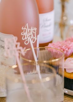 cupcakes and wine bottles on a table with pink frosting in the background