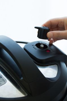 a person is pressing the button on an automatic coffee machine with their thumb and finger