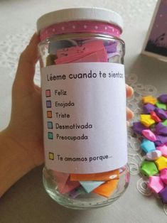 a hand holding a jar filled with lots of colorful confetti next to a card