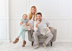 a man, woman and child sitting on a chair with a dog in their lap