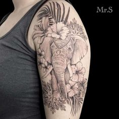 an elephant and flowers tattoo on the arm