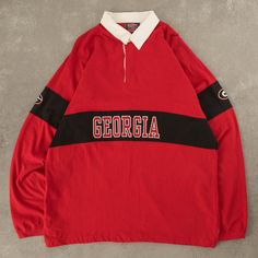 a red and black jacket with the word georgia on it, sitting on a concrete surface