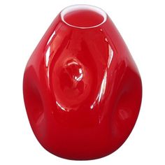 a red vase sitting on top of a white table