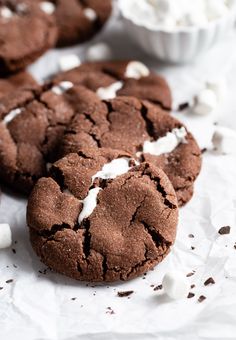 two chocolate cookies with marshmallows on top and another cookie in the background