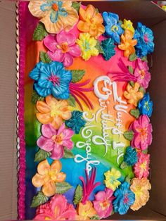 a colorful birthday cake in a box decorated with flowers and the words happy birthday written on it