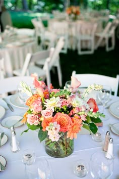 a vase filled with flowers sitting on top of a table covered in plates and glasses