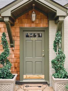 a front door with two planters on either side and a light fixture above it