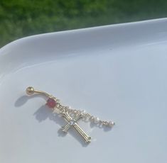 a cross with a red stone hanging from it's side on a white plate