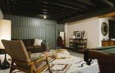 a living room with a pool table, couch and chair in the middle of it