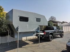 a truck is parked in front of a house shaped like a camper with its door open