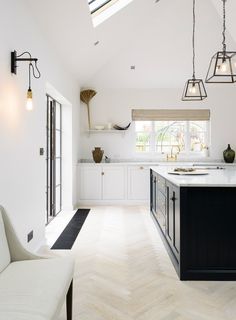 an open kitchen with white cabinets and black counter tops is pictured in this image, there are three hanging lights above the island