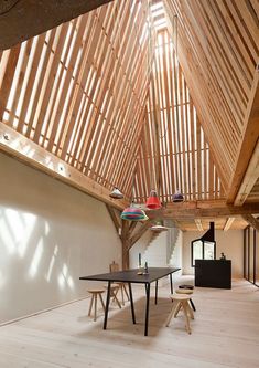 an empty room with tables and chairs in the center, surrounded by wooden beams on the ceiling