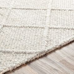 a white rug on top of a wooden floor next to a wood flooring board