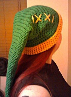 a woman with red hair wearing a green crocheted hat on top of her head