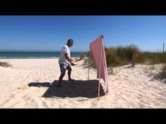 a man standing on top of a sandy beach next to an orange and white flag