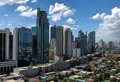 an aerial view of a city with tall buildings in the foreground and clouds in the background