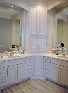 a large bathroom with two sinks, mirrors and cabinets in the middle of the room