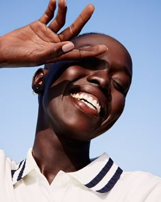 a woman is smiling and holding her hands up to the side with one eye open