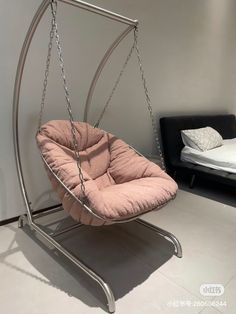 a pink swing chair sitting on top of a white floor next to a black bed