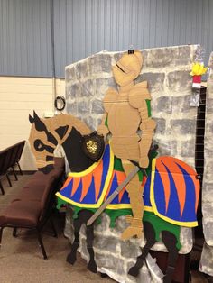 cardboard cutout of a man riding a horse in front of a stone wall with chairs around it