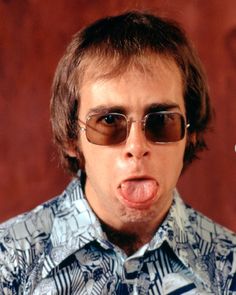 a man wearing sunglasses making a funny face with his tongue hanging out to the side