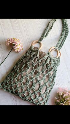 a crocheted purse sitting on top of a white table next to a flower