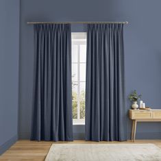 a living room with blue walls and white curtains on the window sill, along with a rug