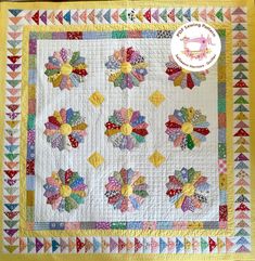 a quilted table topper with colorful flowers on the front and bottom, along with a yellow border