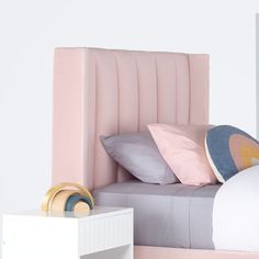 a bed with pink headboard and two pillows on top of it next to a night stand