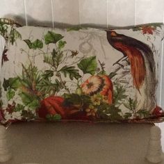 a decorative pillow with birds on it sitting on a chair in front of a wall