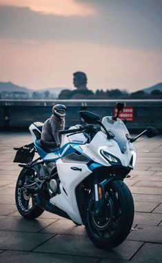 a cat sitting on top of a white motorcycle parked in front of a parking lot