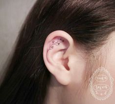 a woman's ear has a small flower tattoo on it