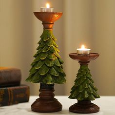 two candles are sitting next to each other on a table with books and a candle holder