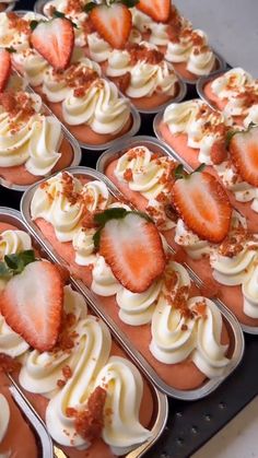 there are many cupcakes with strawberries in them on the tray and one is topped with whipped cream