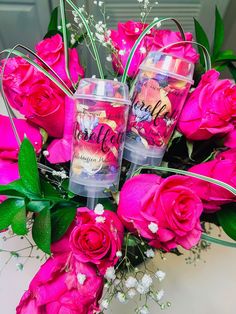 pink roses and two personalized tumbles are arranged on a table