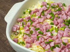 ham and noodles in a white bowl with green onions on the side, ready to be eaten