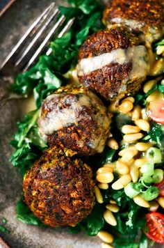 some meatballs are sitting on top of a salad with corn and tomatoes in it