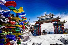 an arch in the middle of a snowy area with flags flying from it's sides