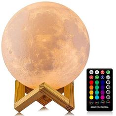 the moon lamp is on top of a wooden stand with remotes next to it