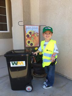 a young boy standing next to a trash can