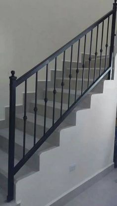 an empty room with white walls and black iron railings on the bottom floor, next to a blue fire hydrant