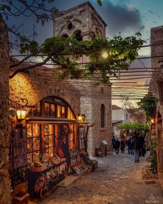 an alley way with people walking around and shops on both sides at sunset or dusk