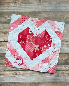 a heart shaped quilt on top of a wooden table