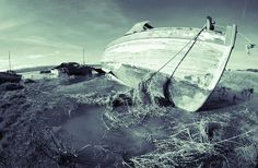 an old boat sitting on top of a dry grass field