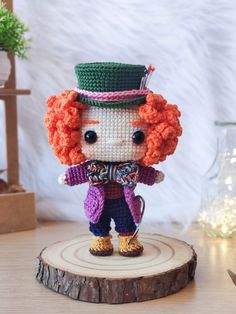 a small crocheted doll is standing on a tree stump in front of a white background