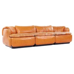 an orange leather couch with two reclinings on the back and one arm extended