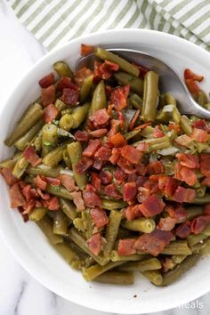 a white bowl filled with green beans and bacon