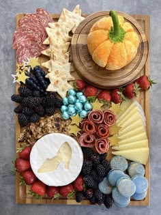 an assortment of cheeses, fruits and crackers on a wooden platter