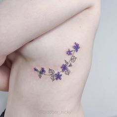 a close up of a woman's stomach with purple flowers on the side and behind her